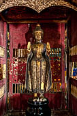 Wat Xieng Thong temple in Luang Prabang, Laos. Small Buddha statue in the entrance porch. 